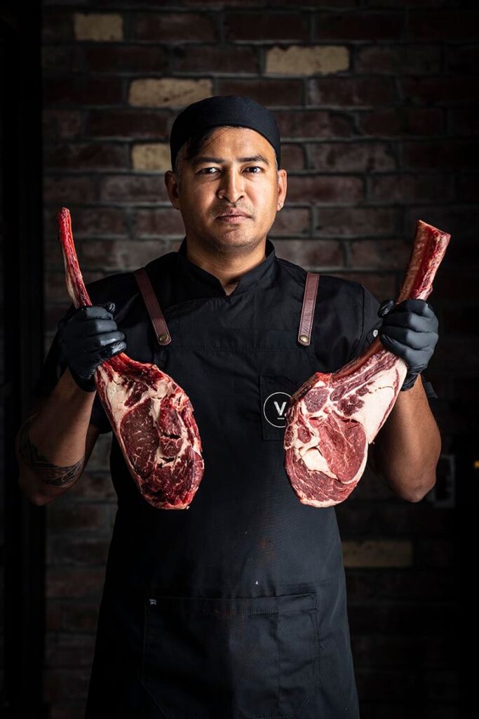 Chef holding Tomahawk steaks